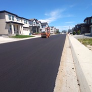 A piece of equipment rides down a newly paved street in the Sagamore neighborhood 