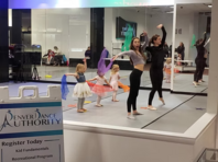 a group of toddlers waving multi colored flags with 2 teachers in a denver dance authority classroom