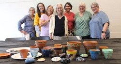 7 senior women pose in front of various pots they painted at the SCC