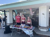 Pool staff members smile by a table at an event