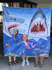 Three people pose with a shark cutout during Family Swim Night in Superior