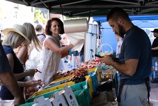 Person grabs a plastic bag to fill with the many ripe produce items laid out on a table in front of her.