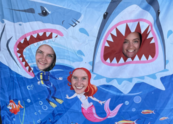Three people pose with a shark cutout at Family Night at the Pool