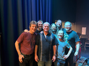 Seven members of The Other Brothers pose on a stage