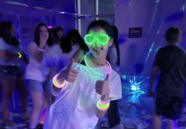 teen girl does two thumbs up for the camera wearing glow in the dark sunglasses at the SCC glow party