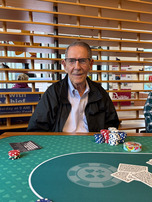 senior man sitting at poker table in front of chips and cards