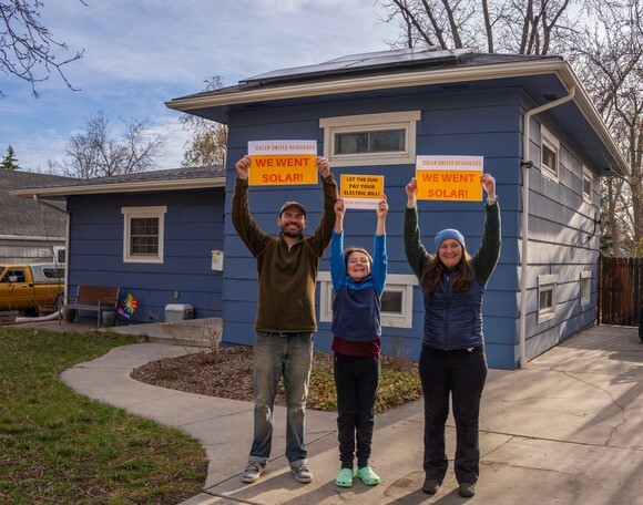 Justin and Rebecca's family, from Longmont, posing in front of their home's solar installation.