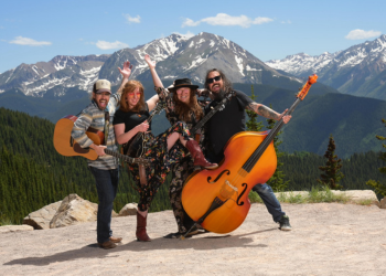 Four band members with Mighty Holler pose with instruments on top of a mountain