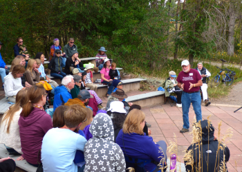 A man tells a story to a crowd in an outdoor amphitheater