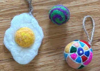 An egg, a purple and green ball, and a multicolored ornament made of wool