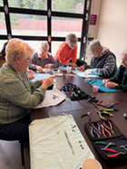group of seniors at the SCC using pliers and other tools to bead necklaces
