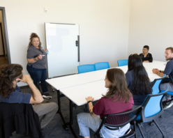 a group of people attending a collaborative lecture from a woman presenting in a conference room