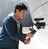 a man using film equipment to videotape a textured wall
