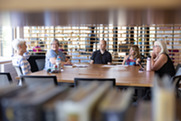 camera peeks thru bookshelf at a group of seniors discussing book club