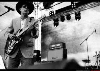 Black and white image of Johnny O performing on stage with a guitar