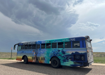A painted bus with words "stop denying, start healing"