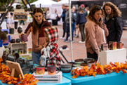 People shop at a table with handmade ceramic mugs and fall decorations