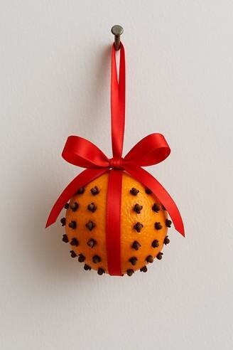 An orange pomander with clove studs and a red ribbon
