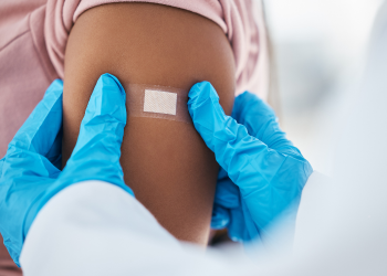 A doctor with blue gloves puts a bandaid on a patient