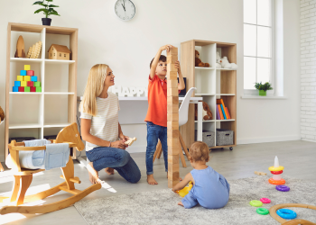 A babysitter plays with blocks with two young children
