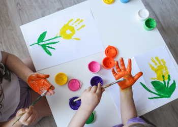 Two kids paint on their hands and pieces of paper