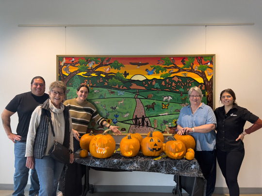 Five people pose with carved pumpkins at the Superior Community Center