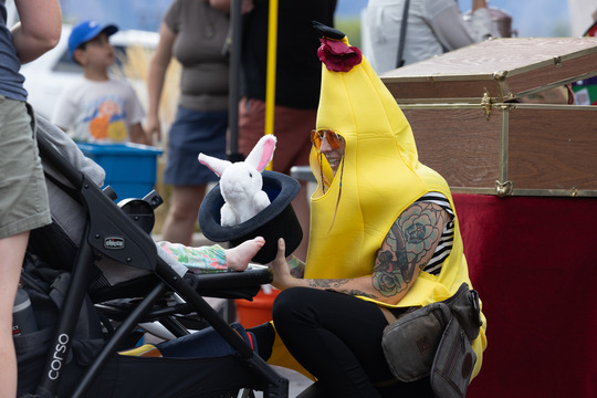 A magician in a yellow banana costume pulls a stuffed rabbit out of a hat for a child