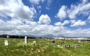 Historic Superior Cemetery tombstones in green grass with a mountain backdrop