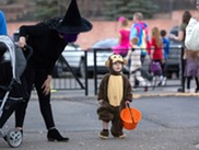 Child in a monkey costume holding candy bag during Monster Mash.