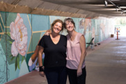 Artists Hilary Williams and Susan Mattson pose in front of a mural they painted in the Rock Creek Parkway underpass