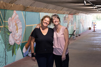 Artists Hilary Williams and Susan Mattson pose in front of a mural they painted in the Rock Creek Parkway underpass