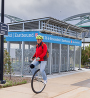 A man in a red jacket and yellow helmet rides a unicycle