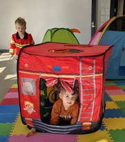 Two young children play in a red inflatable fire truck toy