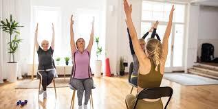 People stretch while sitting in chairs during a chair yoga class