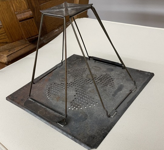Flat metal square base with centered vent holes and four rectangular frames that meet at the top to a smaller metal square.
