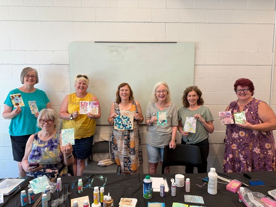 A group of seven Superior Seniors women smile and pose with handmade collages