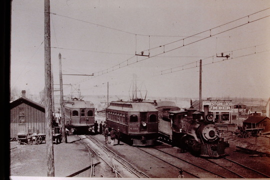 1910 Louisville train station with two electric train cars present, and one steam locomotive.