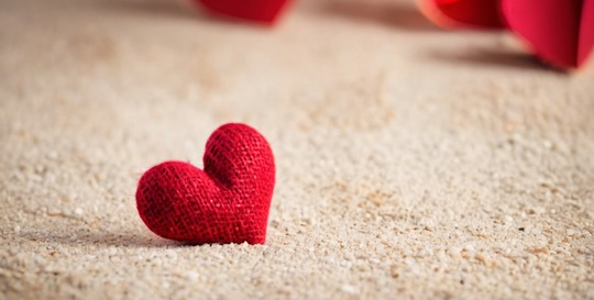 Stitched heart laying in sand.