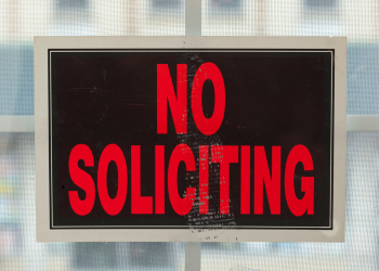 Orange and red No soliciting sign on a window