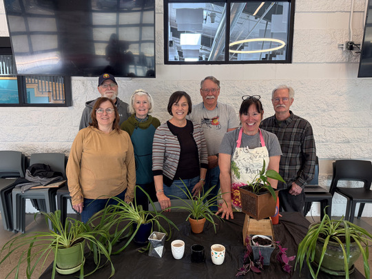 A group of seven Superior seniors pose for a photo with potted plants