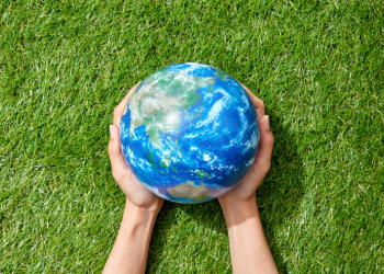 Hands hold a model of the Earth in the grass