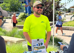 A person talks with guests at a booth at the Conservation Gardens Fair