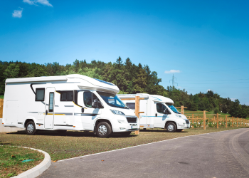 Two white RVs parked in spots on grass