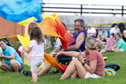 A family smiles and dances with colorful toys during the Summer Concert Series