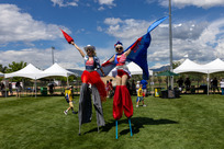 Two women smile for the camera while dressed in red, white, and blue and walking on stilts at the 4th of July Celebration