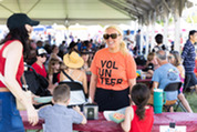 A person in an orange volunteer shirt works the 4th of July event