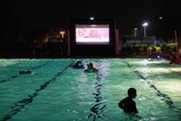 A movie screen illuminated at night at a pool event