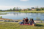 A family has a picnic on a blanket in front of a pond in Boulder County