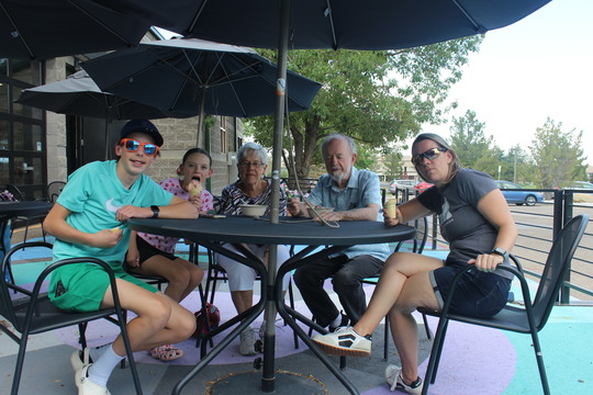 Seniors and their grandkids enjoy ice cream at an outside table