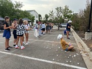 Teens play games in the parking lot outside of the community center